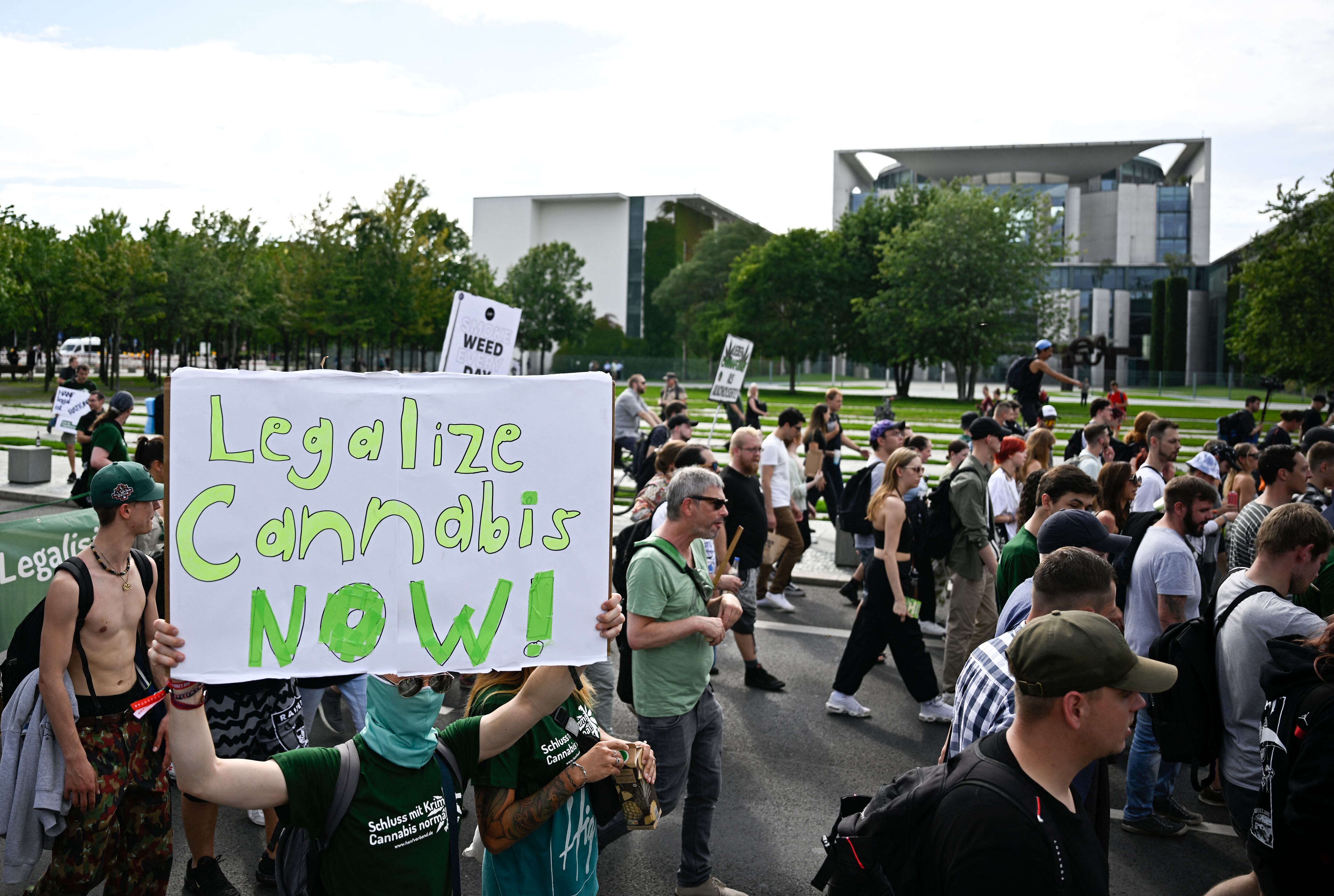 A Participant walks with a sign reading "Legalise Cannabis now" in front of the chancellery during the annual Hemp Parade (Hanfparade), a demonstration for the legalization of hemp, in Berlin's on August 12, 2023. (Photo by Tobias SCHWARZ / AFP)