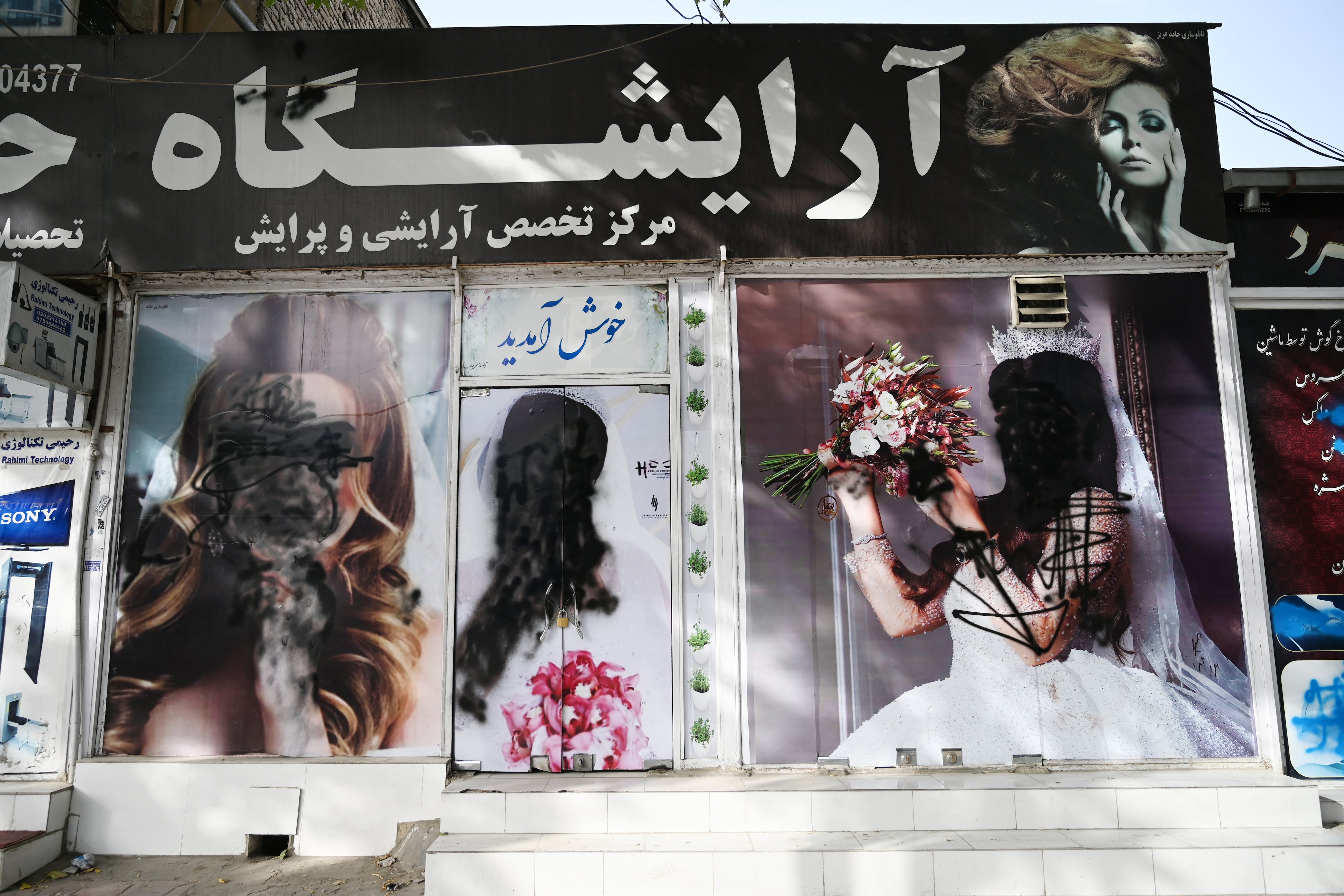 The facade of a beauty salon is pictured with images of women defaced using spray paint in Shar-e-Naw in Kabul on August 18, 2021. (Photo by Wakil KOHSAR / AFP)
