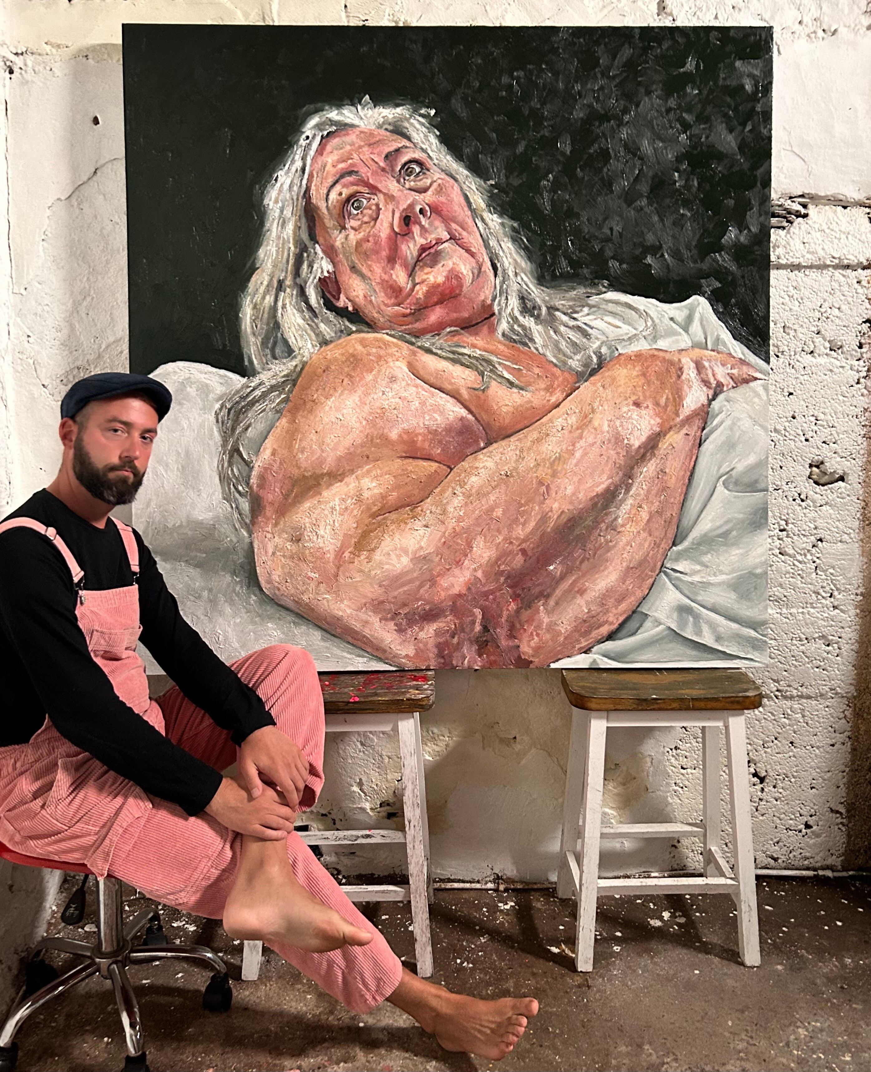 Ian Brennan junto a un retrato cubierto de Sue Tilley, con una sábana blanca que insinúa sin revelar