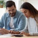 Joven esposo y esposa usando calculadora computadora portátil administrar finanzas calcular facturas hablar de impuestos hacer papeleo juntos sentarse en casa mesa discutir presupuesto de planificación de pago de dinero de préstamo hipotecario familiar