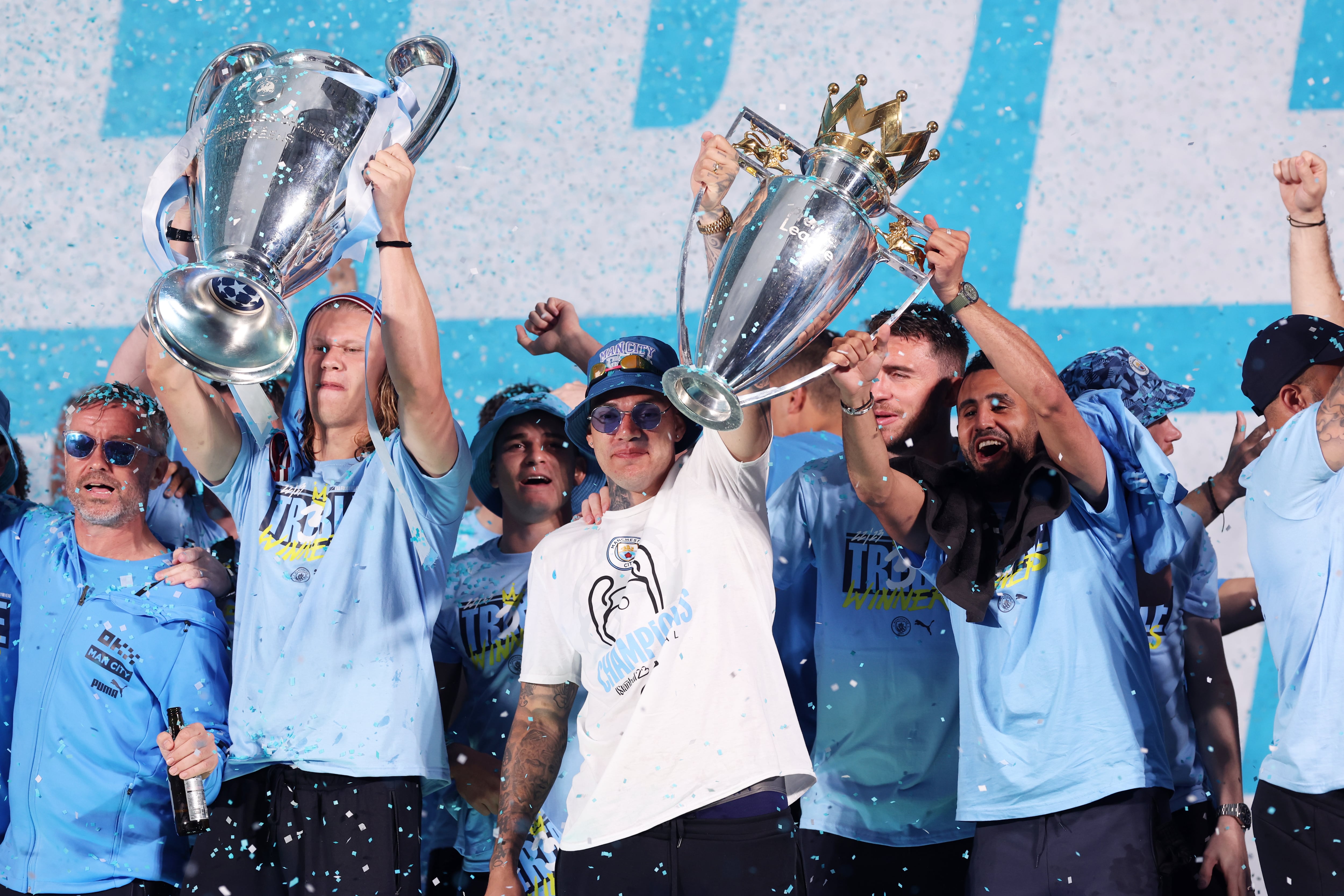 MANCHESTER, ENGLAND - JUNE 12: Erling Haaland lifts the UEFA Champions League Trophy as Ederson and Riyad Mahrez lift the Premier League Trophy on stage in St Peter's Square during the Manchester City trophy parade on June 12, 2023 in Manchester, England. (Photo by Alex Livesey/Getty Images)