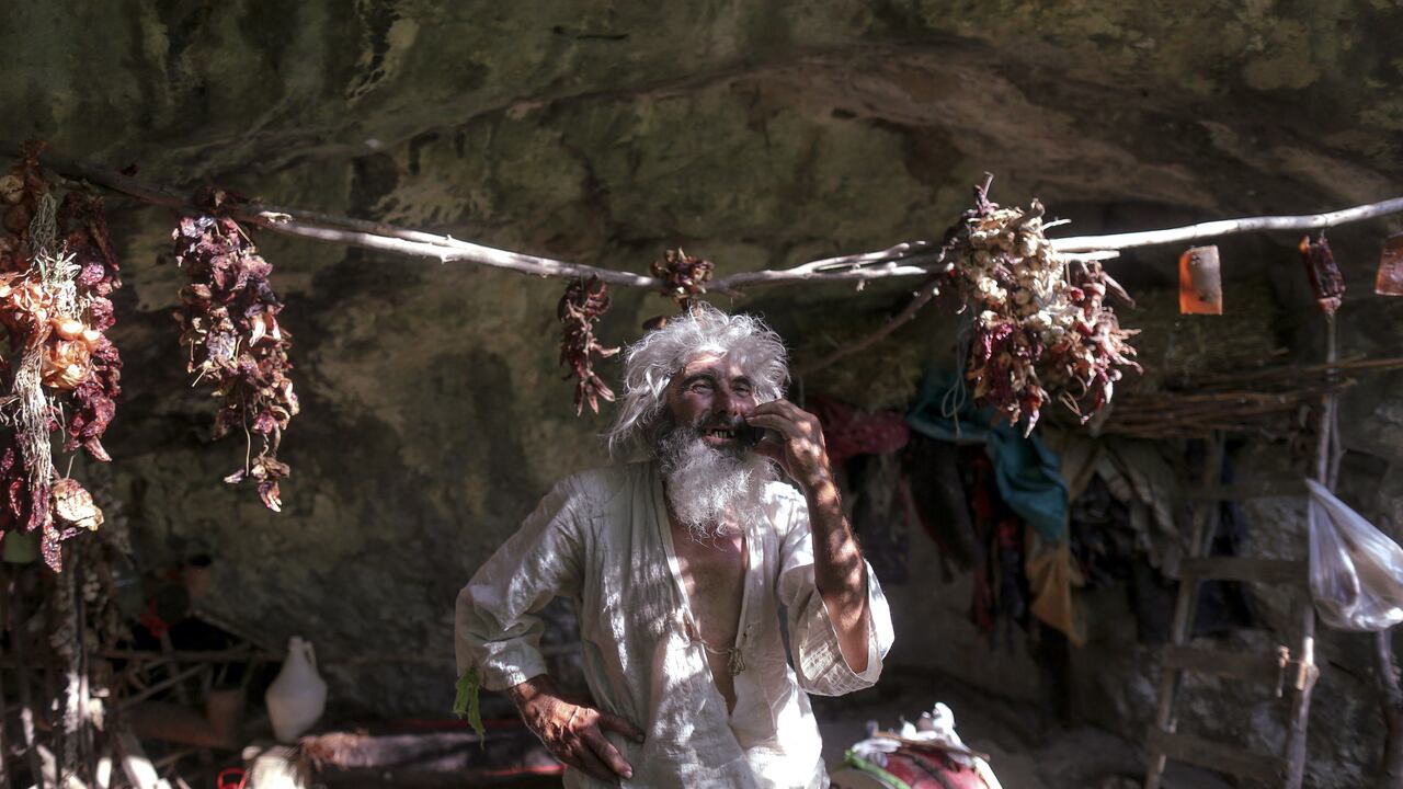 El ermitaño serbio Panta Petrovic da una llamada telefónica con un teléfono celular frente a su cueva en la ciudad de Pirot, en el sur de Serbia. - Hace casi veinte años, Panta Petrovic hizo del distanciamiento social una elección de estilo de vida cuando se mudó a un pequeño Cueva de montaña serbia para evitar la sociedad. El año pasado, en una de sus visitas a la ciudad, el hombre con rastas y barba larga se enteró de que había una pandemia. Después de que las vacunas contra Covid-19 estuvieron disponibles, lo pincharon e insta a todos a hacer lo mismo. (Foto de OLIVER BUNIC / AFP)