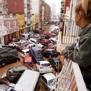 Una mujer mira por su balcón a los vehículos atrapados en la calle durante una inundación en Valencia.