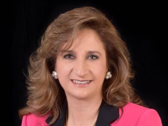 Señora rondando los 50 años vestida en traje de sastre rosa, foto en plano medio.