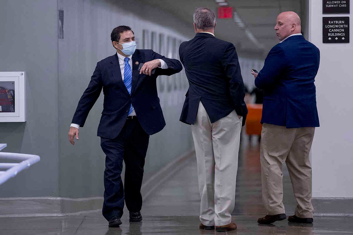 El representante Henry Cuellar, demócrata de Texas, a la izquierda, saluda a otro legislador con un codo mientras camina a la Cámara de Representantes para votar en Capitol Hill, jueves 23 de abril de 2020, en Washington. (Foto AP / Andrew Harnik)