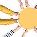 Diversas manos apoyando un tablero redondo amarillo en blanco