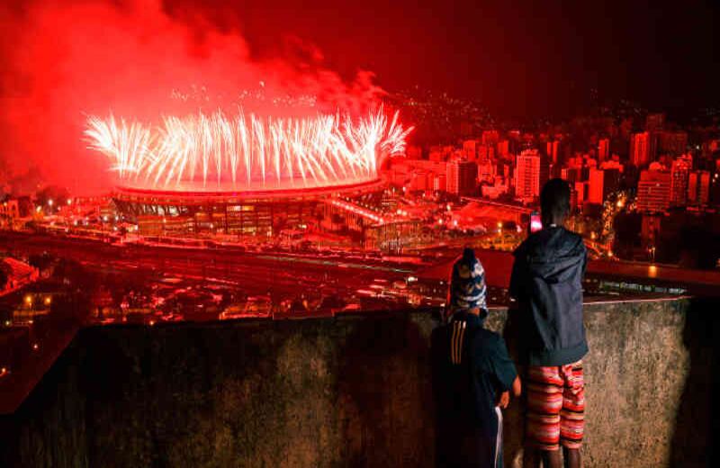 Los Olímpicos, desde la favela. Un fotógrafo de la agencia AFP capturó desde la favela de Mangueira el  contraste de los festejos del Maracaná para la inauguración de las Olimpíadas con la realidad de los barrios marginales de la ciudad brasileña. En la imagen varios niños observan los fuegos artificiales desde la periferia. 