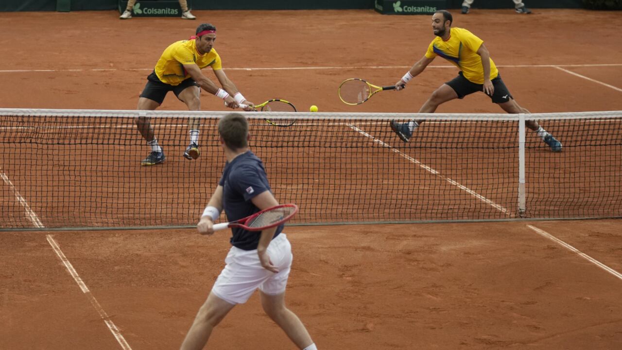 Neal Skupski of Britain, bottom, returns a ball to Robert Farah, left, and Juan Sebastian Cabal, of Colombia, during their Davis Cup qualification doubles match in Cota, Colombia, Saturday, Feb. 4, 2023. (AP Photo/Fernando Vergara)