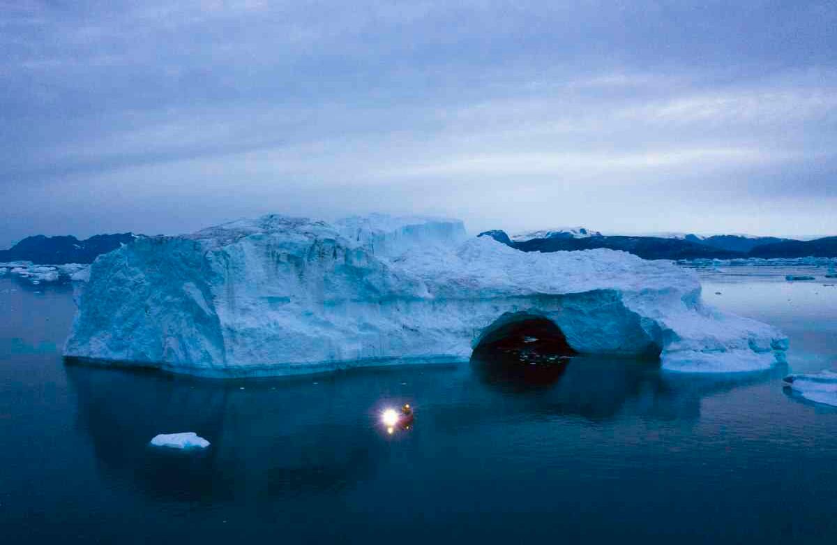 Un barco navega por la noche cerca de un amplio iceberg en el este de Groenlandia, el viernes 15 de agosto de 2019. Groenlandia se ha derretido más rápido en la última década y este verano ha sufrido dos de los derretimientos más grandes registrados desde 2012. (AP Photo / Felipe Dana)