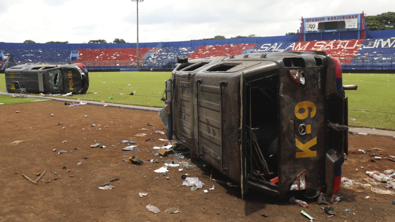 Police cars lie on their side wrecked on the pitch at Kanjuruhan Stadium in Malang, East Java, Indonesia, Sunday, Oct. 2, 2022. Panic at an Indonesian soccer match Saturday left over 100 people dead, most of whom were trampled to death after police fired tear gas to prevent violence. (AP/Trisnadi)