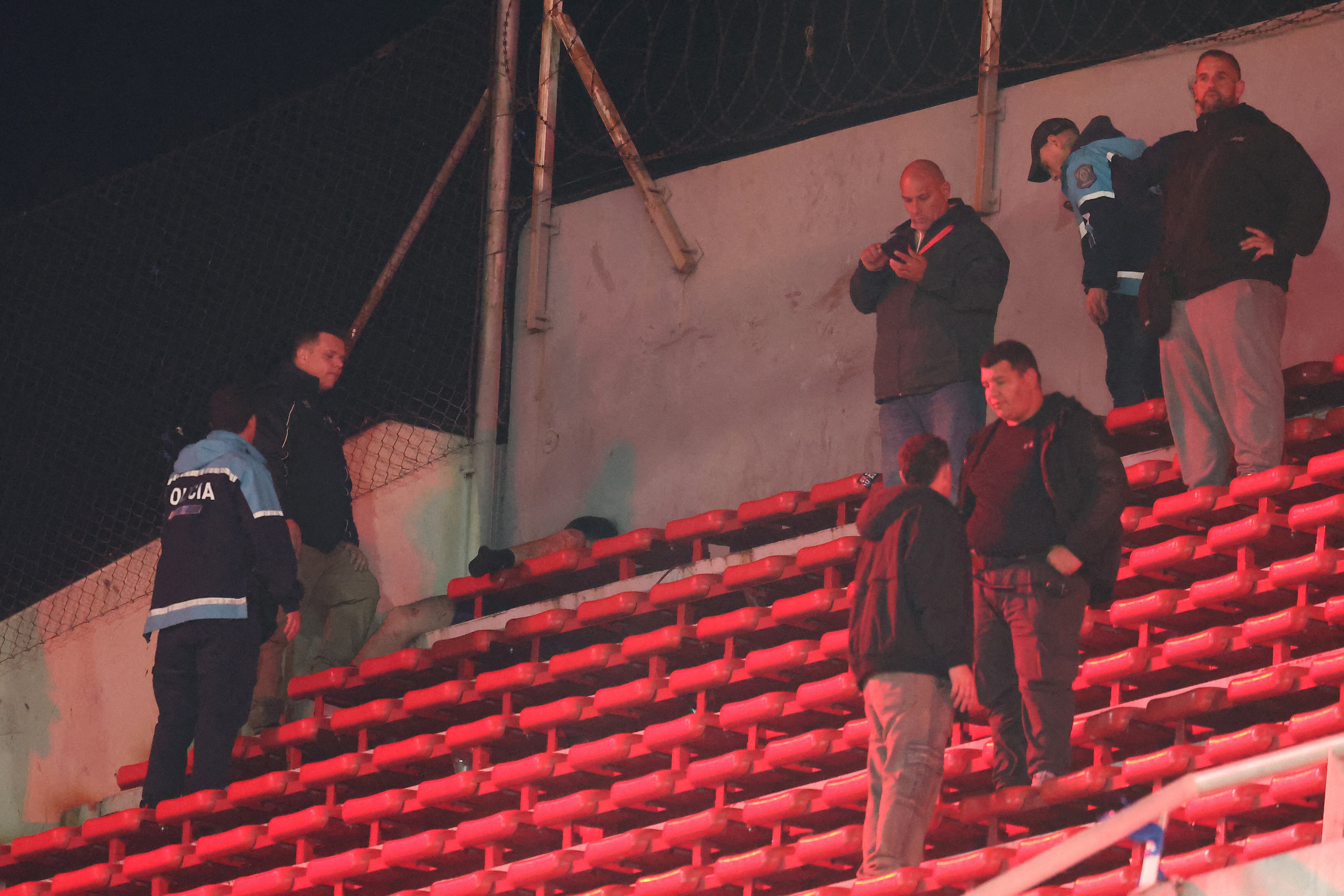 Policías argentinos custodian a personas heridas en las gradas durante la interrupción del partido de vuelta de los octavos de final de la Copa Sudamericana entre Independiente de Argentina y la Universidad de Chile de Chile en el estadio Libertadores de América en Avellaneda, provincia de Buenos Aires, Argentina, el 20 de agosto de 2025. (Foto de Alejandro PAGNI / AFP)