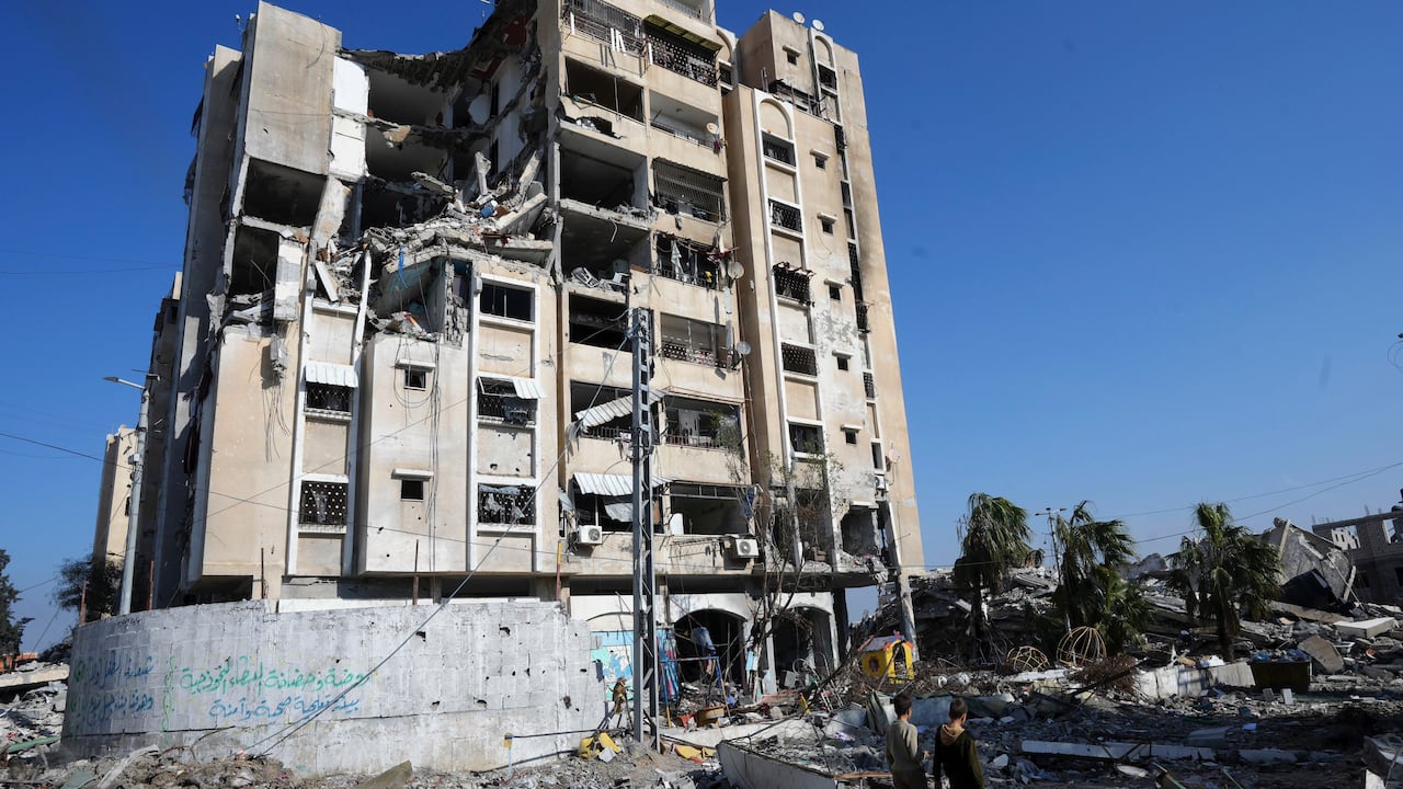 Palestinos caminan entre la destrucción causada por el bombardeo israelí en el campo de refugiados de Nusseirat en la Franja de Gaza, el viernes 19 de enero de 2024.