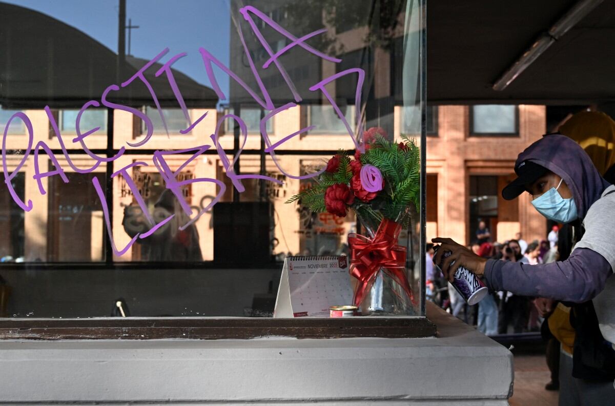 Un manifestante pinta un CAI, en la calle 72 de Bogotá, durante una protesta en solidaridad con los palestinos y para condenar la interceptación de la Flotilla Global Sumud por parte del ejército israelí en Bogotá el 2 de octubre de 2025