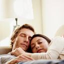 Loving mid adult couple sleeping on sofa at home