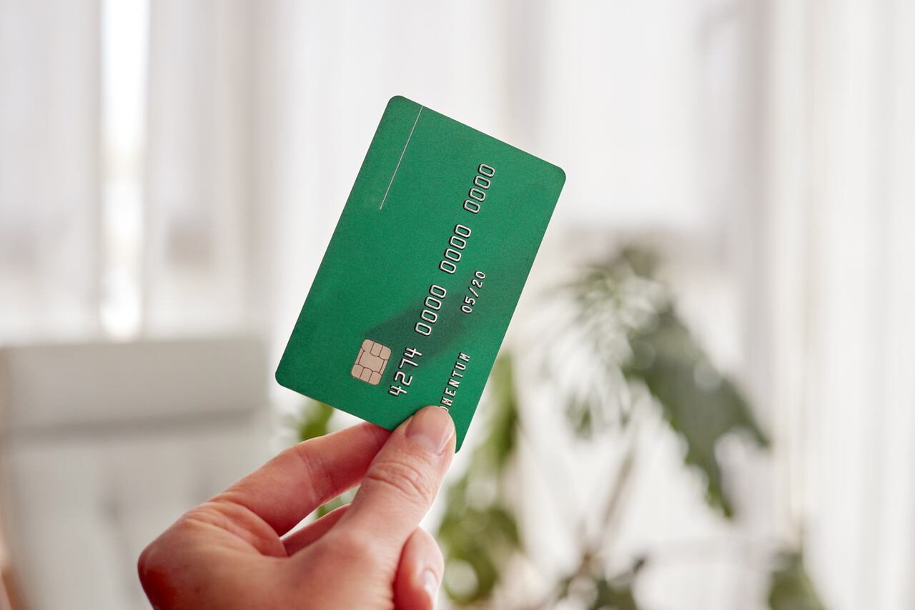Close up female hand hold green credit card on white background with clipping path