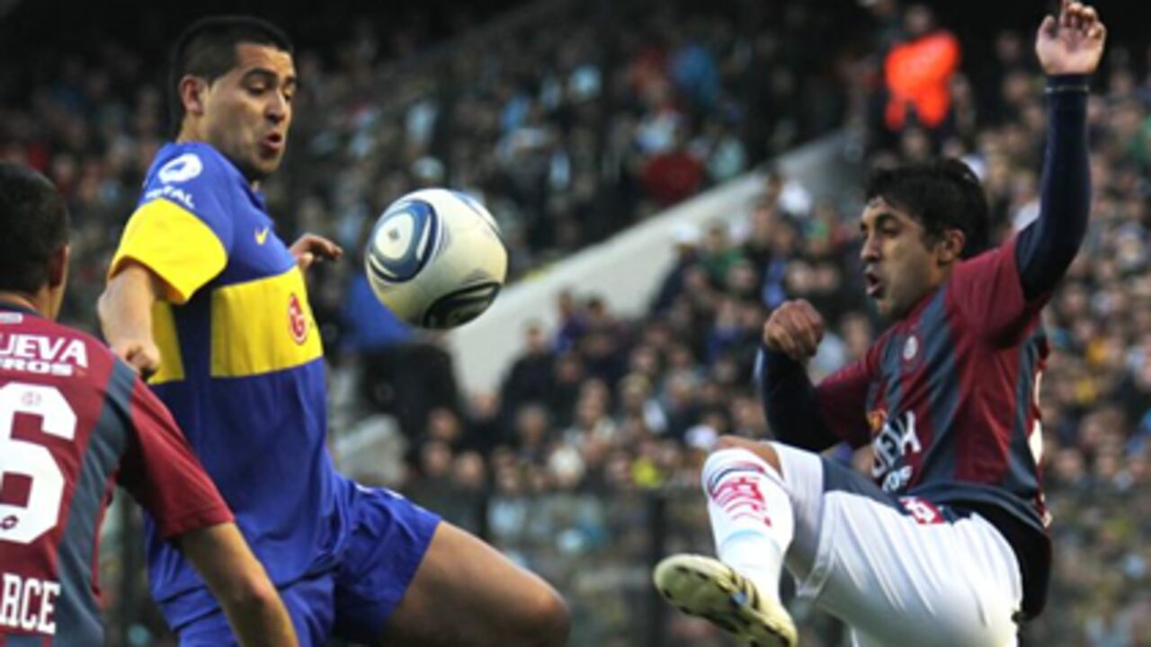 Juan Román Riquelme (i) disputa el balón frente a Gabriel Méndez (d) de San Lorenzo.