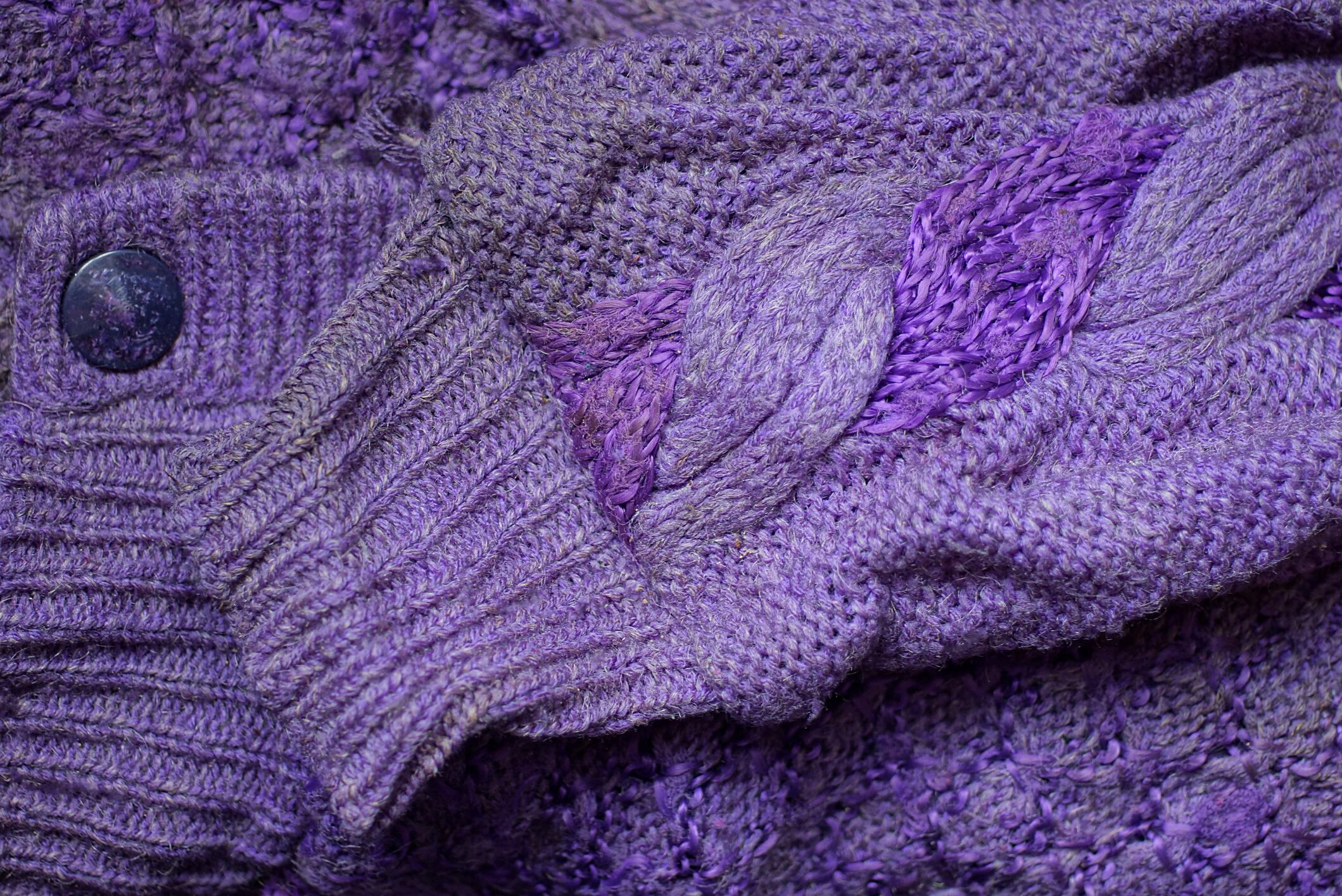fabric texture of lilac wool knitted sweater with dirty old sleeve and button