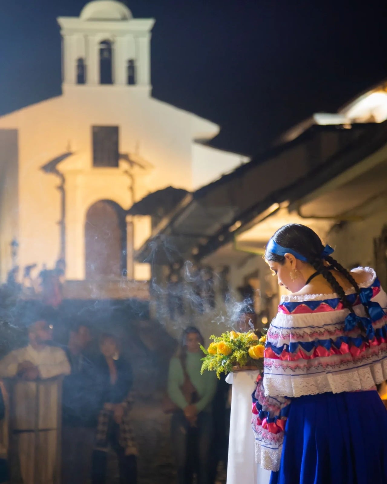 Sahumadora llevando flores amarillas e incienso al inicio de la procesión del Lunes Santo en Popayán.