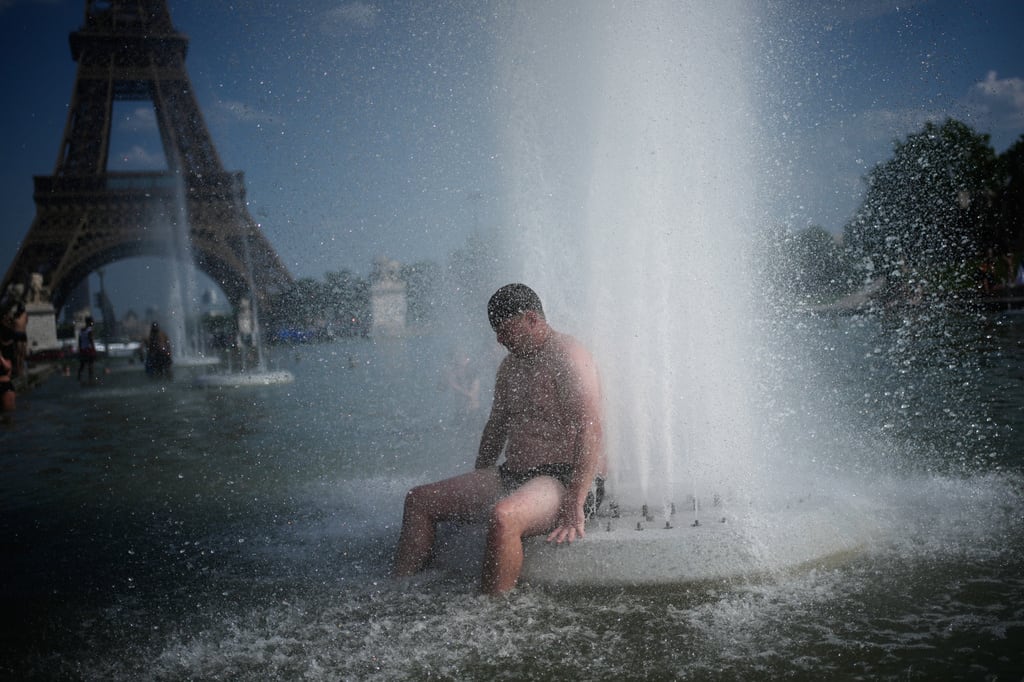 Una persona se refresca en una fuente en el Trocadero, cerca de la Torre Eiffel, durante una ola de calor, en París.