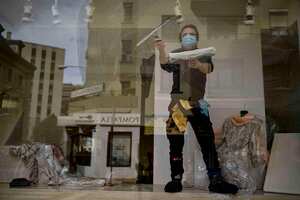 Un trabajador que usa una máscara facial para protegerse contra el coronavirus limpia el vidrio de una tienda de ropa, en Pamplona, norte de España, el martes 12 de mayo de 2020. Aproximadamente la mitad de 47 millones de españoles están entrando en una versión más suave del estricto encierro y el coronavirus del país. Están comenzando a socializar, comprar en pequeños (AP Photo / Alvaro Barrientos)