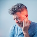 male having ear pain touching his painful head isolated on gray background
