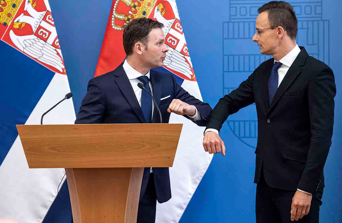 El ministro de Asuntos Exteriores y Comercio de Hungría, Peter Szijjarto, a la derecha, y el ministro de Finanzas de Serbia,  Sinisa Mali, a la izquierda, se despiden con un llamado 'saludo de corona'.  (Zsolt Szigetvary / MTI vía AP)