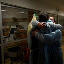 Chaplain Kevin Deegan, left, and registered nurse Michelle Stephens comfort each other in a COVID-19 unit at Providence Holy Cross Medical Center in the Mission Hills section of Los Angeles on Saturday, Jan. 9, 2021. "He is my friend. He is a trusted co-worker. He is my partner in crime. We absolutely have been through a lot together," said the nurse. (AP Photo/Jae C. Hong)