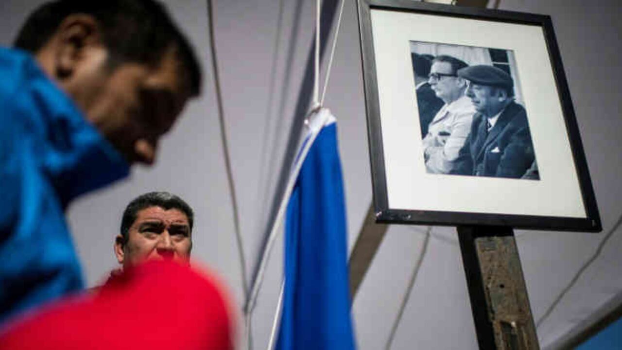 Miembros de la Fundación Pablo Neruda cuelgan una foto del poeta (izq.) con el presidente Salvador Allende durante una ceremonia en Isla Negra, a unos 120 km al oeste de Santiago, el 26 de abril de 2016. Foto: AFP | Archivos | Martin Bernetti.