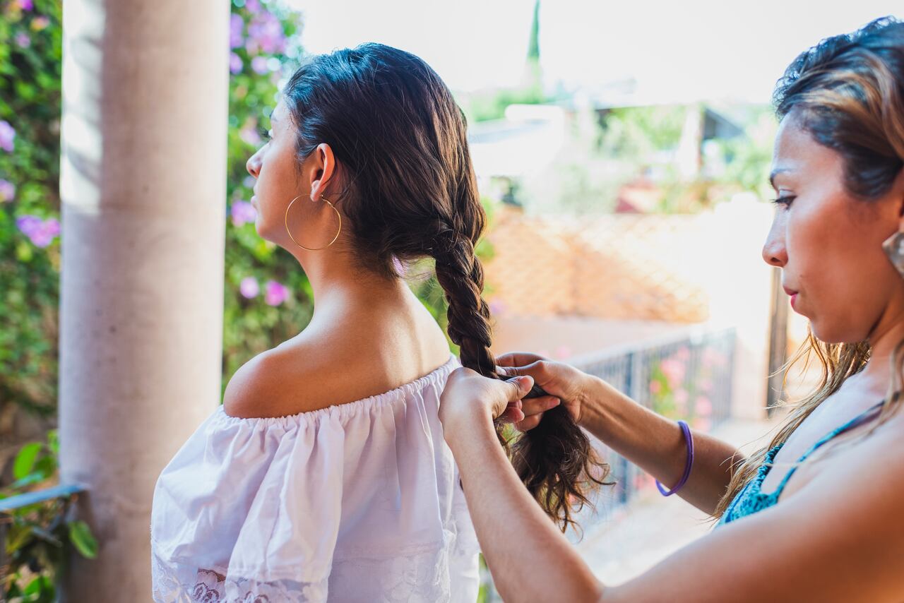 Mother braiding the hair of teenage daughter
