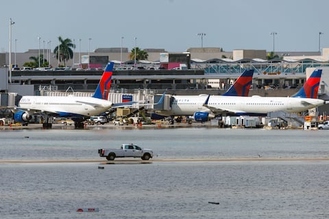 Aviones de Delta Air Lines en su terminal mientras un camión atraviesa la pista inundada del Aeropuerto Internacional de Fort Lauderdale-Hollywood