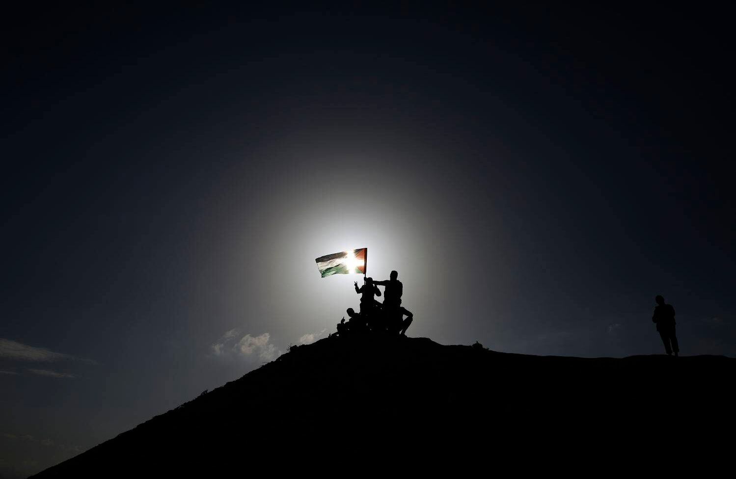 Palestina El conflicto sin fin Protestantes palestinos izan su bandera nacional durante unos enfrentamientos con soldados israelíes cerca a la frontera de Gaza.  AFP/ Mohammed Abed 