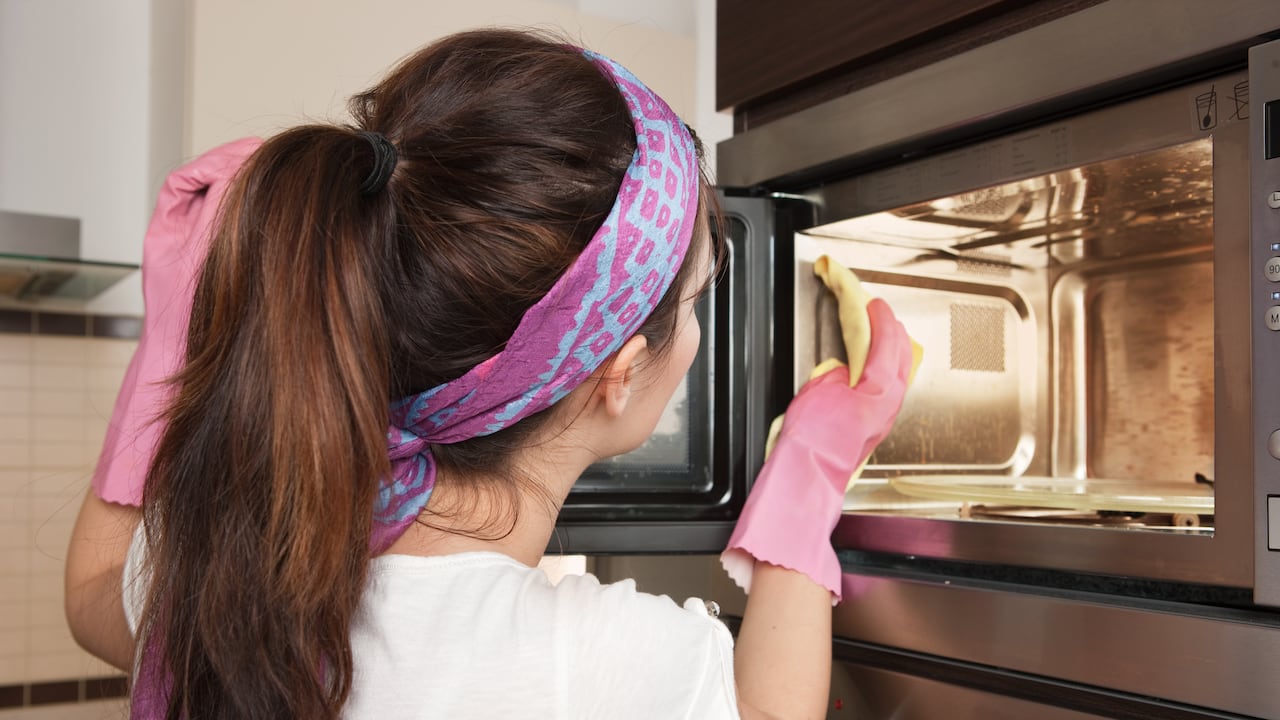 Imagen de referencia de mujer limpiando el microondas.
