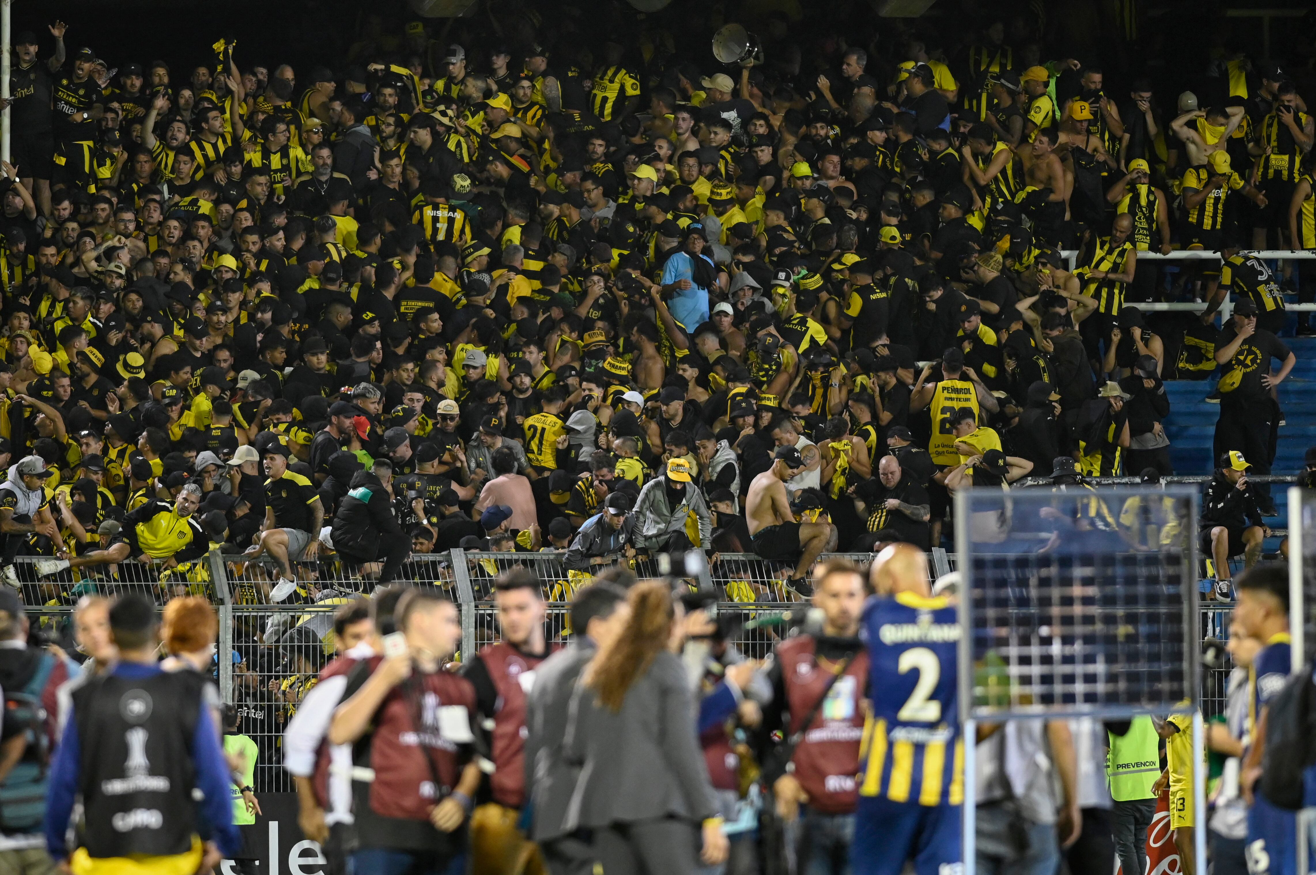 Fans of Pe�arol clash with the police on the stands during the Copa Libertadores group stage first leg football match between Argentina's Rosario Central and Uruguay's Pe�arol at the Gigante de Arroyito Stadium in Rosario, Argentina, on April 4, 2024. (Photo by Marcelo Manera / AFP)