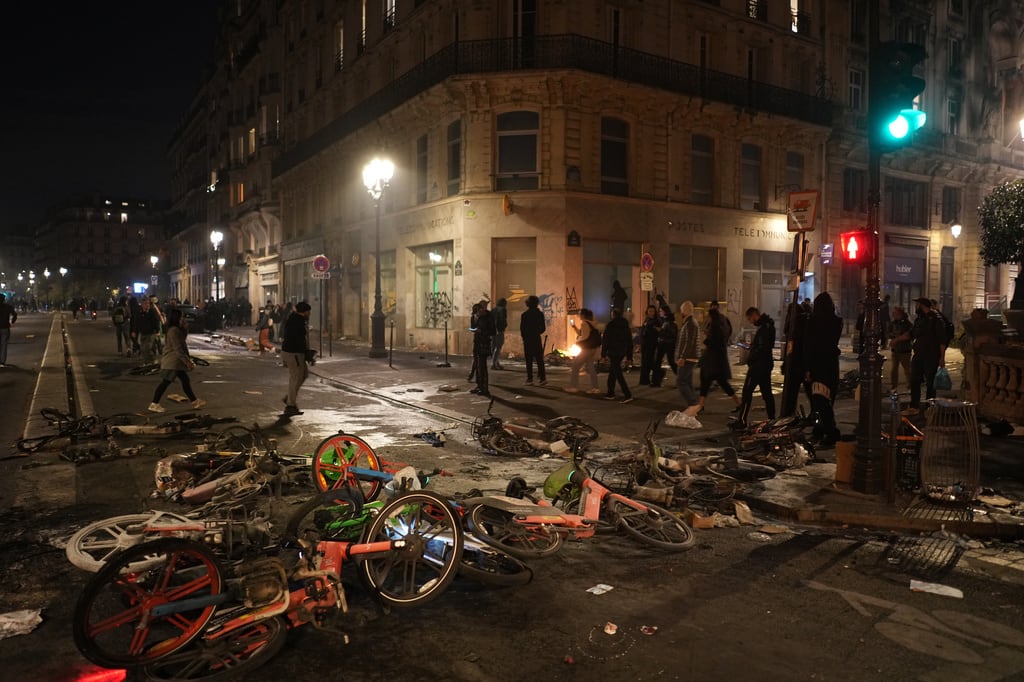 Unas personas pasan junto a bicicletas tiradas en la calle tras una manifestación contra el aumento del costo de la vida