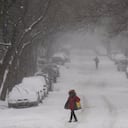 A pedestrian walks across a snow cover street in the Brooklyn borough of New York, Monday, Feb. 1, 2021. (AP Photo/John Minchillo)