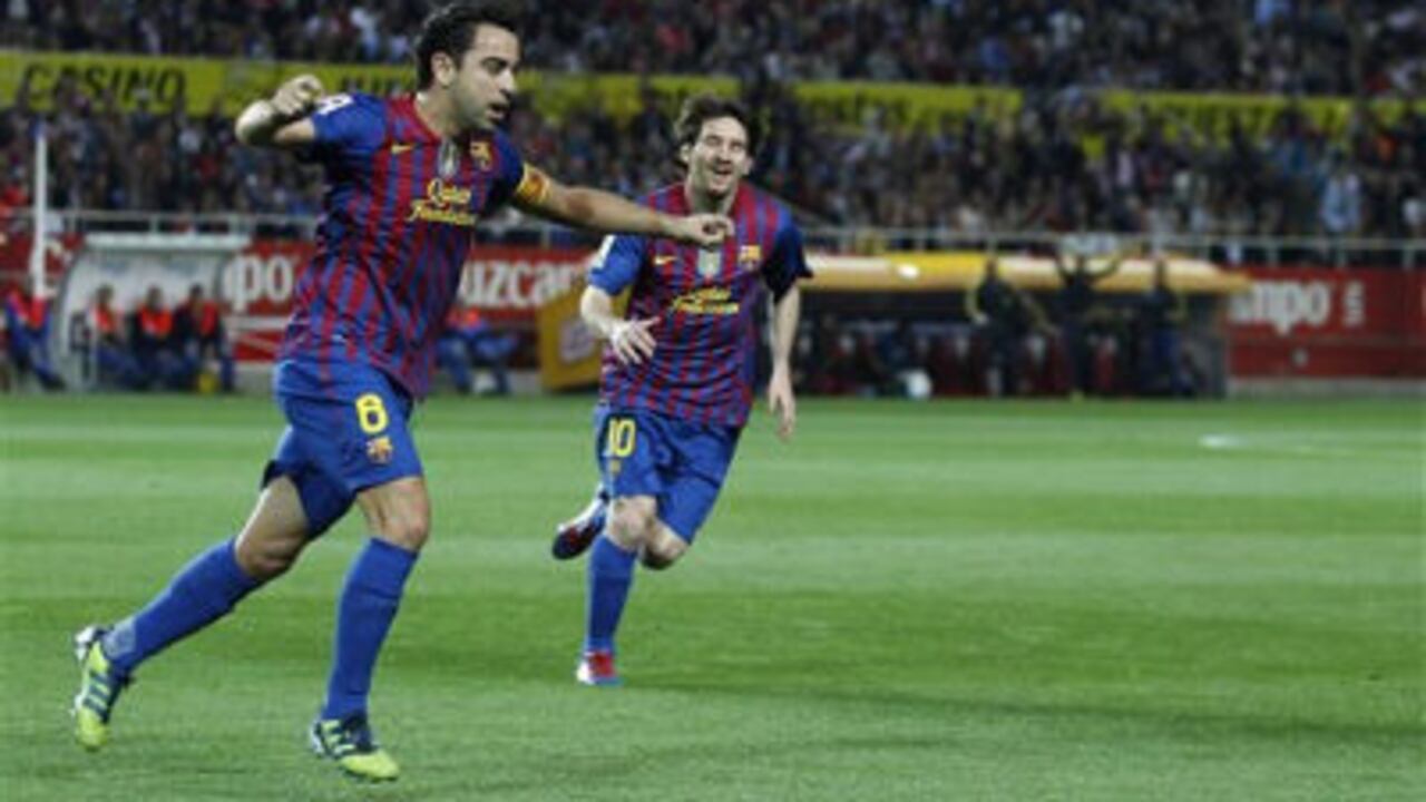 Xavi Hernández (i), celebra tras anotar contra el Sevilla junto con Lionel Messi (d).