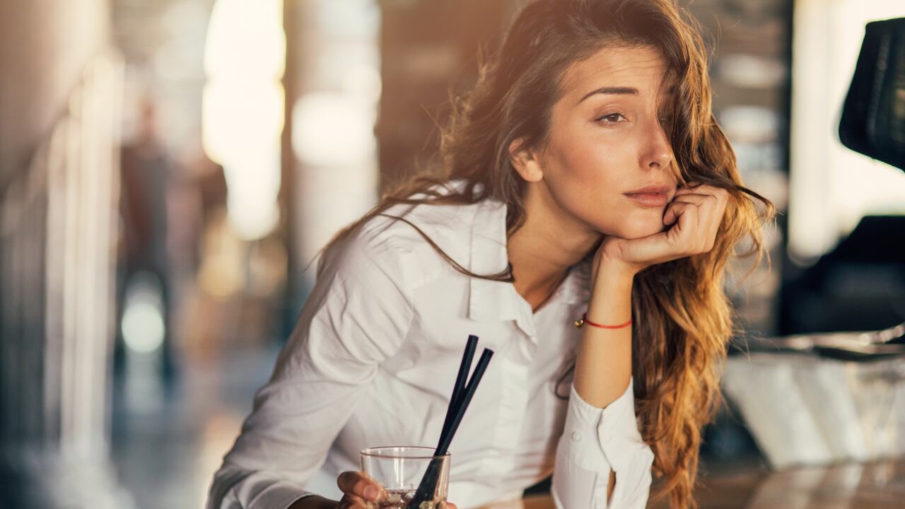 Bored woman drinking cocktail at a bar.
