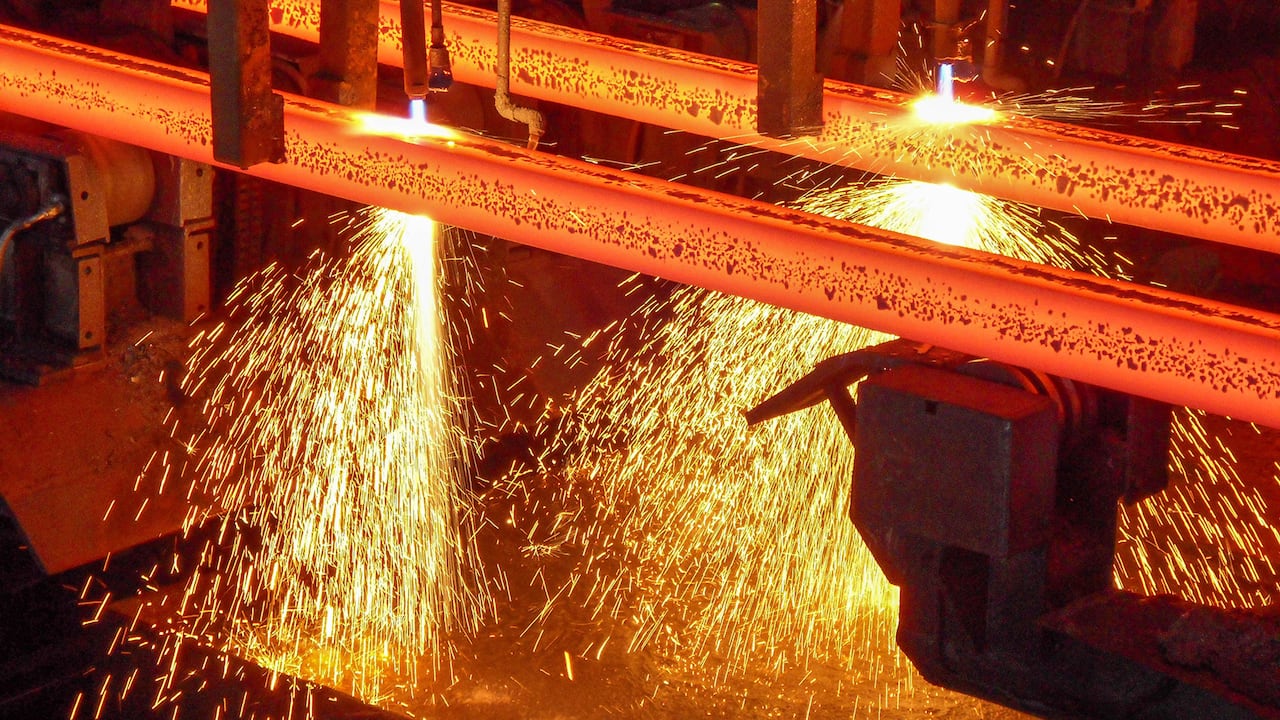 Palanquillas de acero al rojo vivo con chispas en una máquina de colada continua en corte con soplete en un sitio de producción de una planta de acero