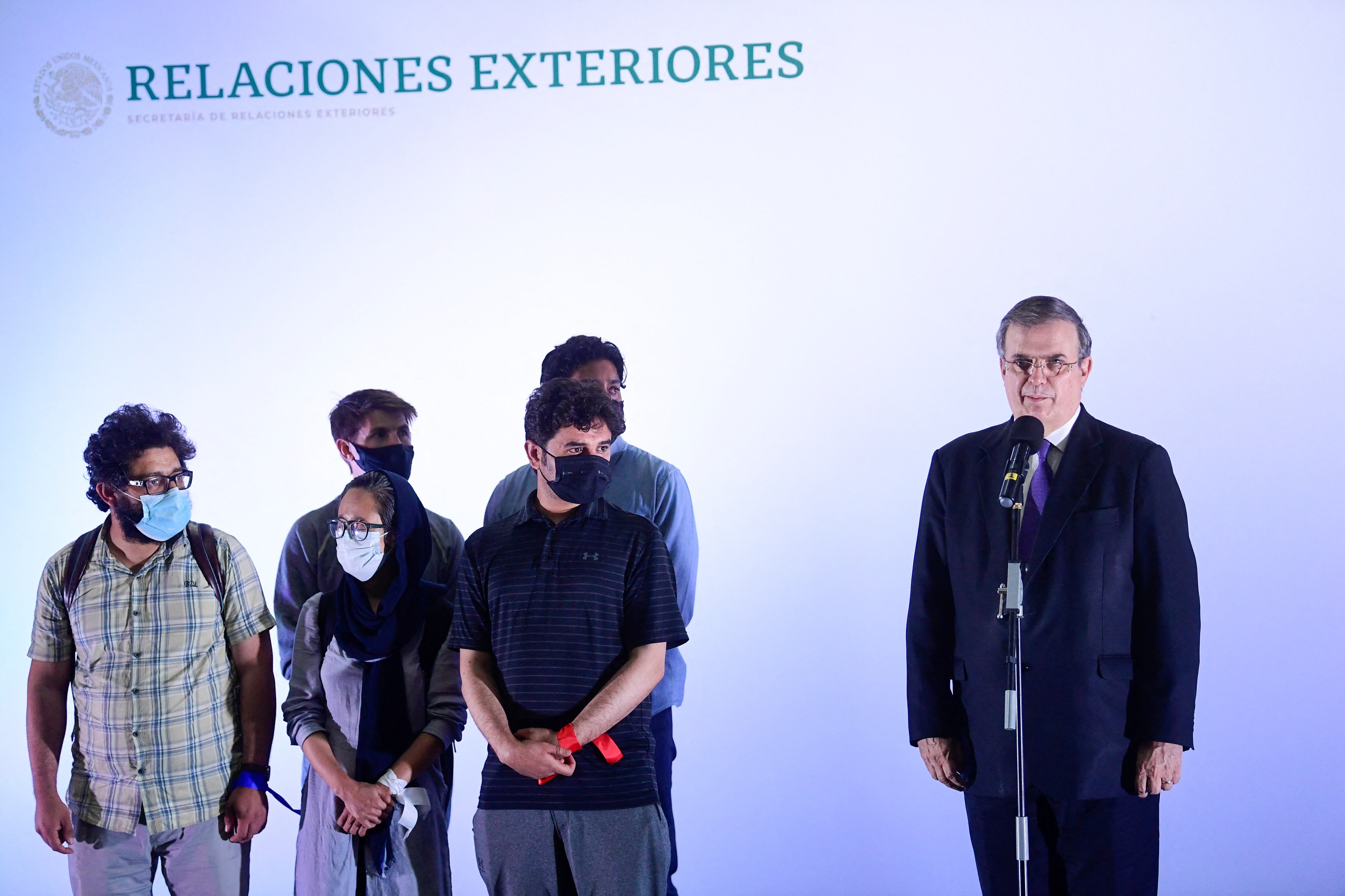 Mexican Foreign Minister Marcelo Ebrard (R) welcomes a representation of 124 correspondents, reporters and staff who worked in various media in Kabul and have requested a humanitarian, refugee or asylum visa from the Mexican government, at the Benito Juarez International Airport in Mexico City on August 25, 2021. (Photo by PEDRO PARDO / AFP)