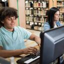 Grupo de estudiantes latinoamericanos investigando en línea usando computadoras en una biblioteca y luciendo muy felices - conceptos educativos