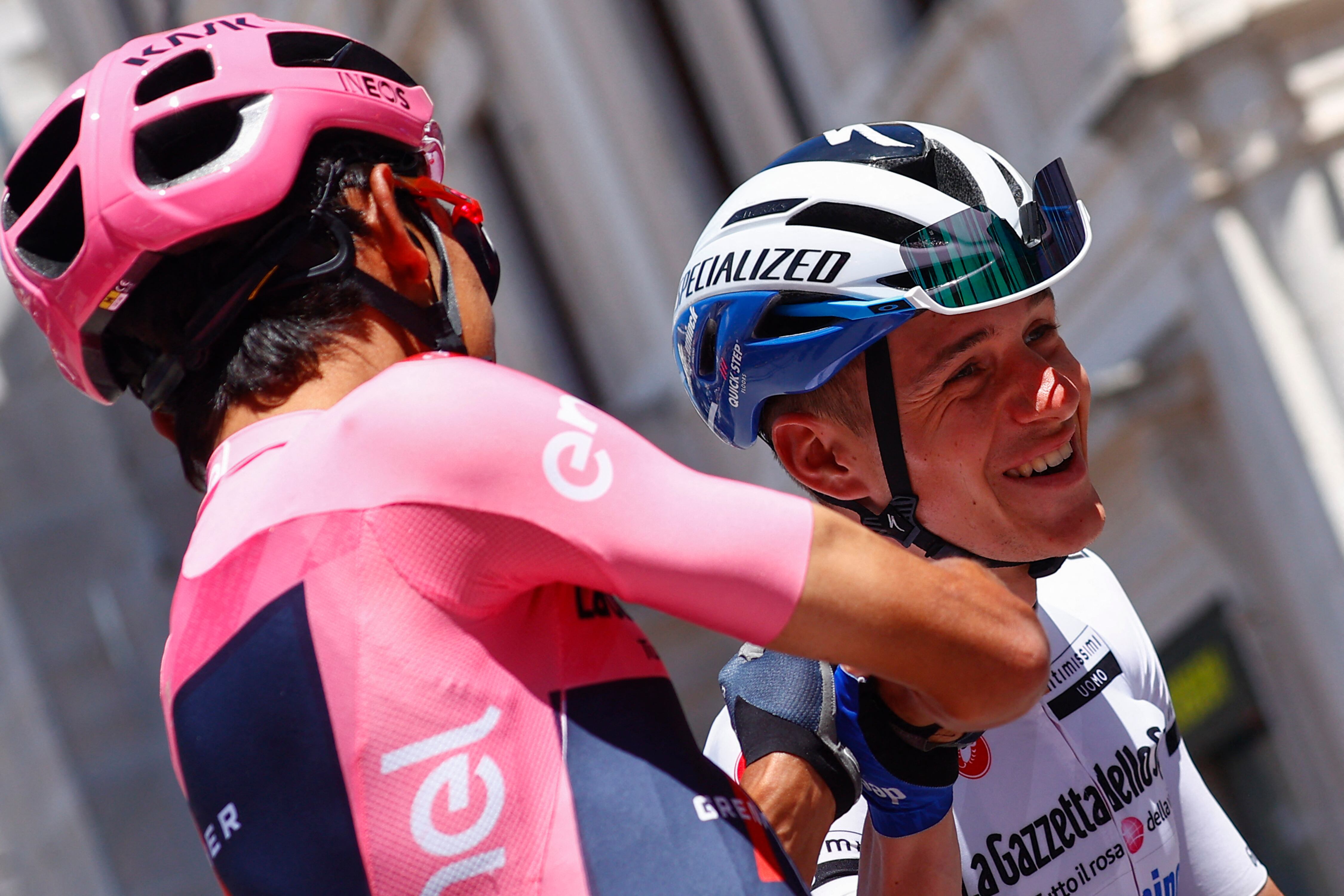 El líder de la general, el ciclista colombiano del Team Ineos, Egan Bernal (izq.), Ayuda al ciclista del equipo Deceuninck al belga Remco Evenepoel con su casco antes del inicio de la décima etapa de la carrera ciclista del Giro de Italia 2021, 139 km entre l'Aquila y Foligno el 17 de mayo. , 2021. (Foto de Luca Bettini / AFP)