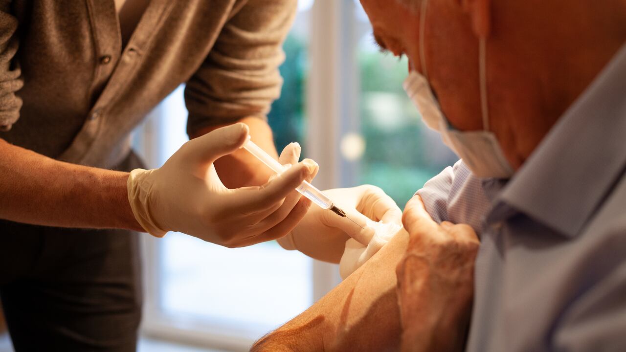 Visita médica domiciliaria: hombre mayor que recibe inyección / vacunación.