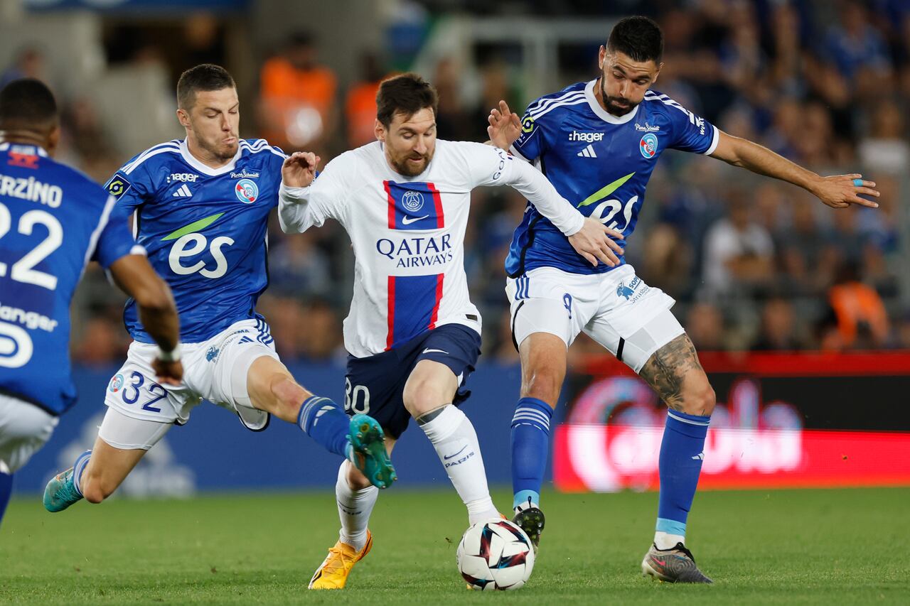 Lionel Messi (centro) del Paris Saint-Germain pugna el balón con Frederic Guilbert (izquierda) y Kevin Gameiro (derecha) de Estrasburgo en el empate 1-1 en el partido de la liga francesa, el sábado 27 de mayo de 2023. (AP Foto/Jean-Francois Badias)