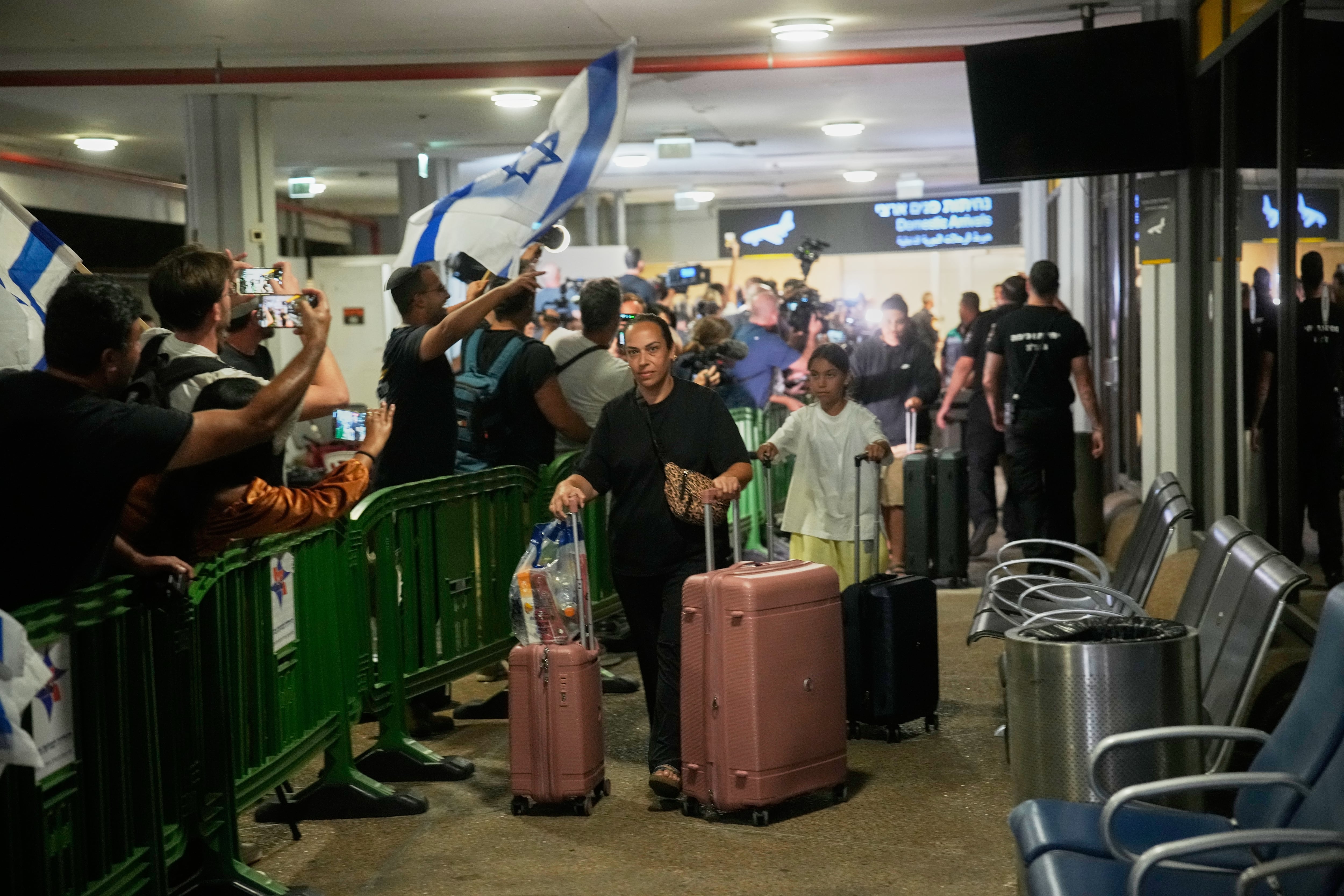 Personas con banderas israelíes se congregan en la puerta de llegadas para recibir a los pasajeros israelíes que viajaban a bordo de un avión de FlyDubai que realizó un aterrizaje de emergencia en Arabia Saudita