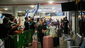 Personas con banderas israelíes se congregan en la puerta de llegadas para recibir a los pasajeros israelíes que viajaban a bordo de un avión de FlyDubai que realizó un aterrizaje de emergencia en Arabia Saudita