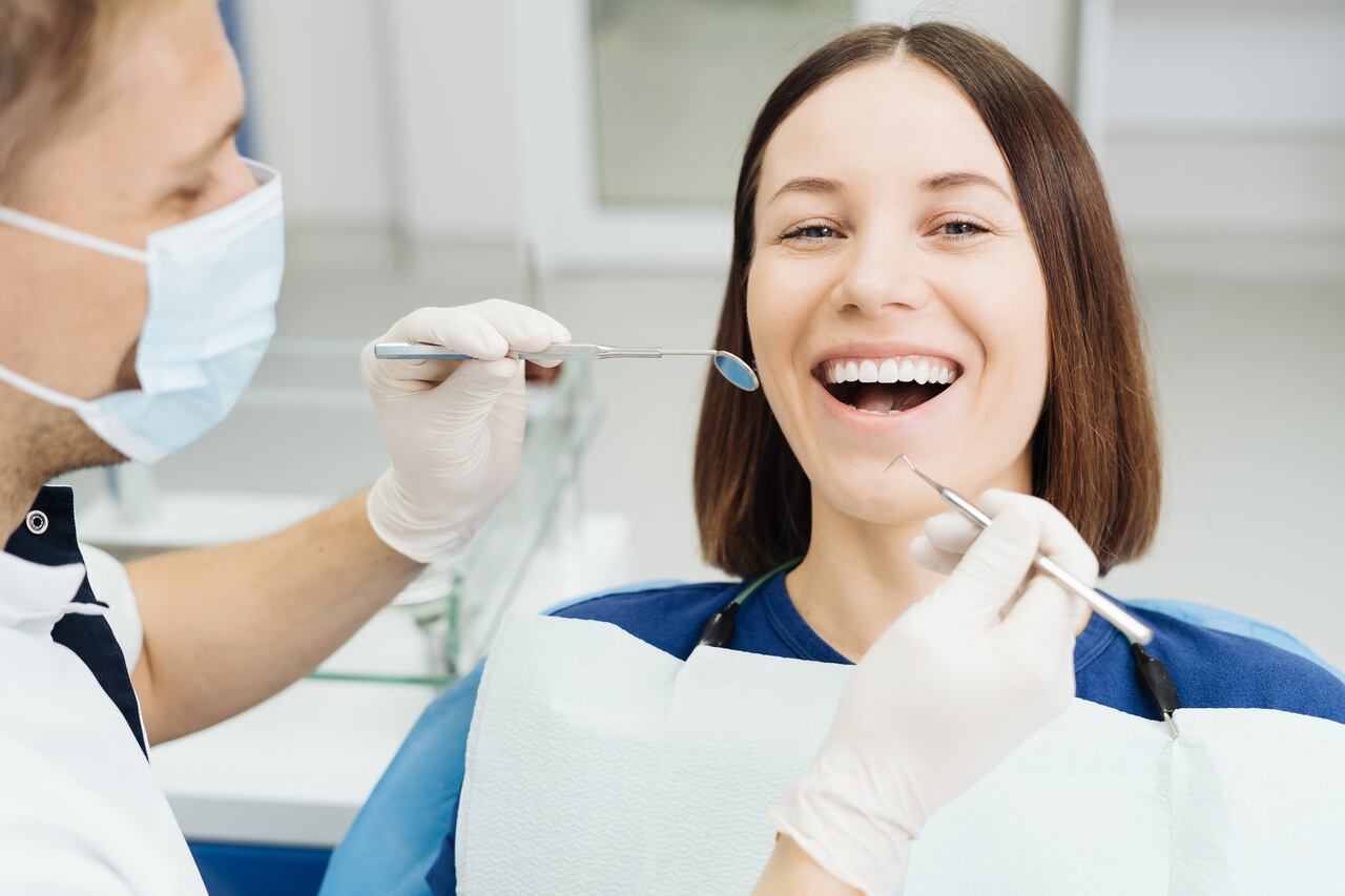 Caucasian male dentist examining young woman patient's teeth at dental clinic. Doctor probing teeth with dental instrument using an explorer look for cavities treatment and checking problems