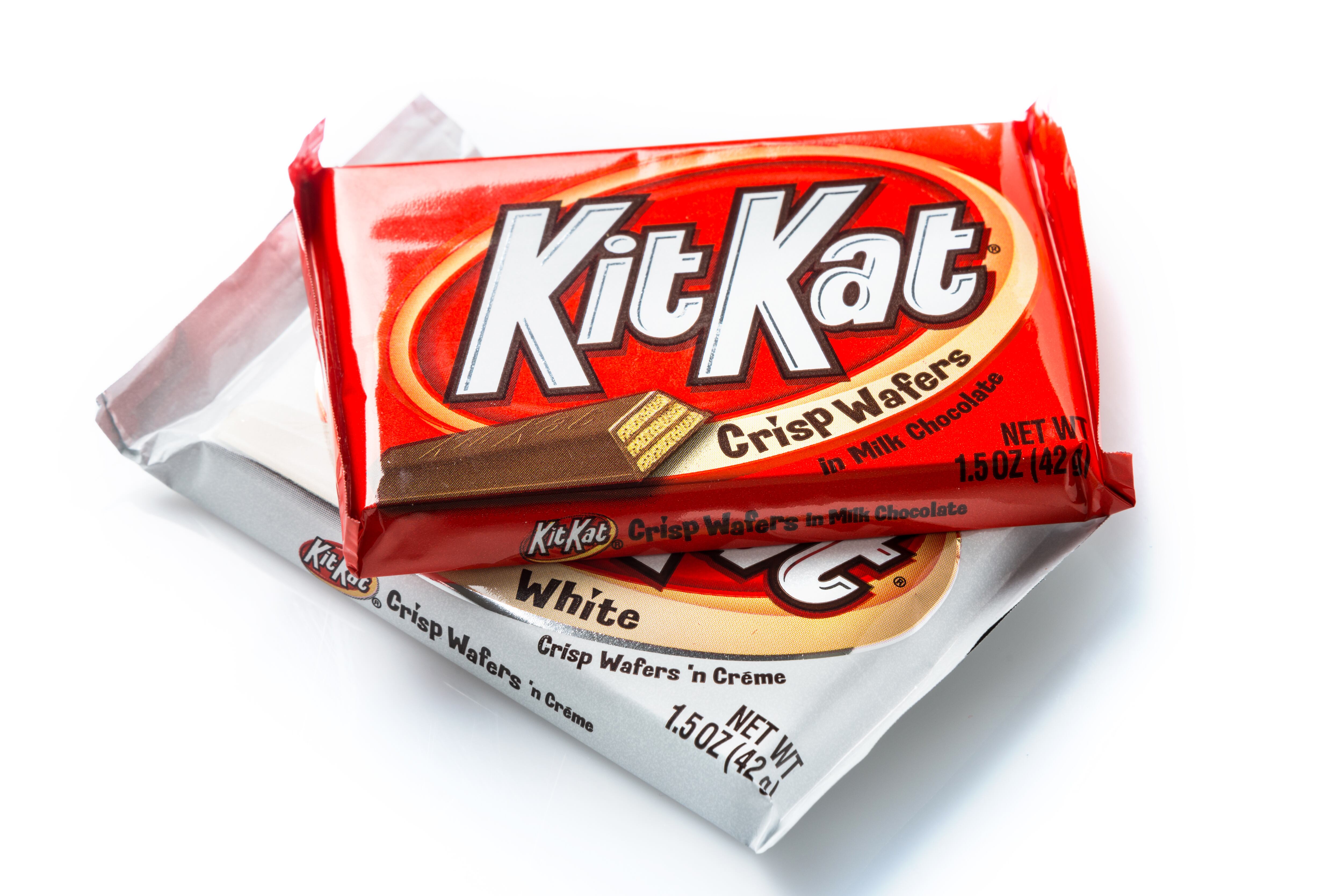Imagen de dos paquetes de barquillos crujientes Kit Kat, uno hecho con chocolate con leche y el otro con crema blanca.