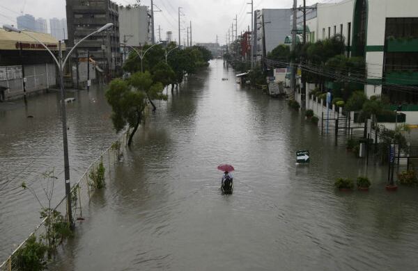 Residentes usan un pequeño bote para transportarse a través de una calle inundada al norte de Manila, capital de Filipinas. (AP) 