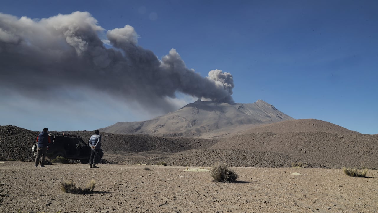La gente observa una pila de humo y cenizas que se elevan desde el cráter del volcán Ubinas, ubicado en la región de Moquegua, en el sur de Perú, el 5 de julio de 2023.