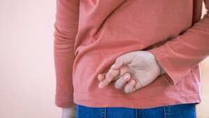 Niña cruzando los dedos detrás de la espalda sobre un fondo claro con espacio para copiar. Mentira y engaño, concepto mentiroso. Día de los Inocentes